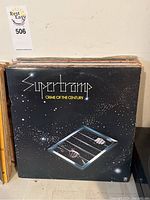 Front cover of Supertramp Crime of the Century vinyl record, showing album title with stars and a barred window with hands behind it.