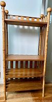 Full view of the bamboo framed etagere shelf showing all four pine shelves and bamboo posts with rounded finials.