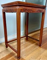 Side view of the Chinese hardwood side table showing the slender legs, carved apron design, and wood grain detail.