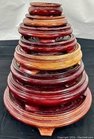 Stack of 10 wooden round display base stands showing size gradient and wood grain color variation.