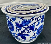 Front view of largest planter showing prominent blue floral and leaf motifs on white porcelain.