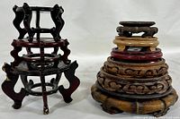 Three rosewood fish bowl planter stands and six carved wood stands shown stacked and side by side.