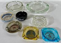 Overview of nine vintage ashtrays including clear, amber, black, blue, and gray-blue glass. Several feature Las Vegas casino logos.