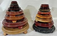 Two stacks of carved wooden display stands in different sizes and wood tones, showing range from 10 inches to 2 inches, with carved feet and smooth finishes.