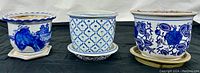 Three ceramic blue and white planters arranged side-by-side showing various Oriental floral and bird patterns.