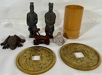 Overview photo showing the entire lot of oriental decorative articles including statues, brush jar, frog, stone piece, horse figurine, and large decorative coins.