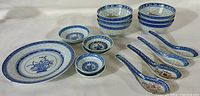 Full overview of porcelain rice bowls, plate, and spoons showing blue and white design and arrangement