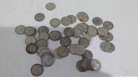 Overall view of 50 Canadian silver dimes spread on white surface showing worn circulated condition and consistent size and design typical of pre-1967 minting.