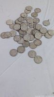 Scattered view of majority of the 50 silver quarters on white background