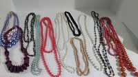 14 beaded costume jewelry necklaces laid out, showing variety of colors and beads
