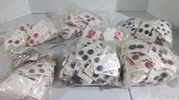 Top view showing dozen plastic bags filled with multiple cardbacks of unused buttons of various colors and styles.