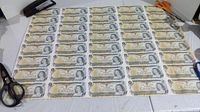 Full sheet front view showing 8 columns by 5 rows of uncut one dollar bills, with scissors and stapler at edges
