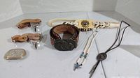 Photo showing all items including two belts, belt buckle, spurs, bolo tie, and necklace, all western themed