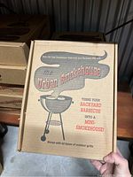 Closed cardboard box labeled The Urban Smokehouse showing branding and product purpose as mini smokehouse for backyard barbecues.