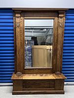 Front view of antique oak hall tree with large rectangular mirror and wood framing, metal hooks visible on inner columns.