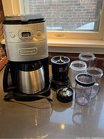Front and side view of Cuisinart coffee maker with thermal carafe and Magic Bullet blender components on counter.