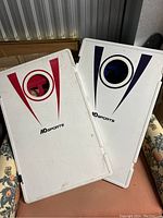 Photo of front sides of two cornhole boards with red and blue markings and holes