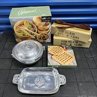 Set items arranged for overview showing boxed Pomerantz wooden salad bowls with wooden utensils, two boxes with wooden serving utensils, metal serving bowl with lid, rectangular metal serving tray, boxed wooden butter paddle and pusher set