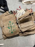 Bundles of small burlap bags showing printed designs and drawstrings tied together.