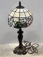 Full view of the stained glass lamp showing stained glass shade, metal stem, and electrical cord.