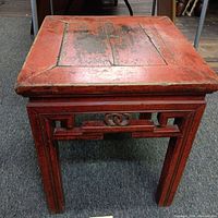 Side angle view of rustic wooden side table showing carved apron detail and distressed top