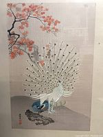 Close-up of the white peacock with fanned tail feathers and blue peacock on rock, showing details of silk texture and painted branch with orange leaves.