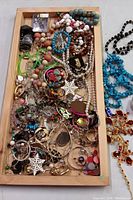 Full tray showing a wide assortment of colorful beads, pins, earrings, and other costume jewelry items piled together