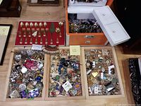 Overview of wooden trays with large assortment of costume jewelry and gold plated flatware box