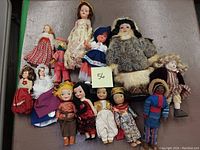 Group of 13 vintage multicultural collector dolls arranged on a surface showing a variety of styles and sizes.