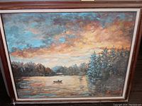Framed oil painting showing entire lake scene with canoeist, forest, and sunset sky.