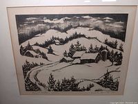 Framed black and white lithograph of a rural winter scene with snow, trees, cabins, and hills, signed and numbered by Isabella Reynolds.