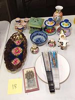 Overview of all ceramic items including tray, cups, shakers, covered jars, bowl, creamer, green ceramic piece, and Asian fans.