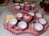 Full view of the pink spongeware demitasse teaware set including large tray, sugar bowl, creamer, and eight cups arranged on a table.