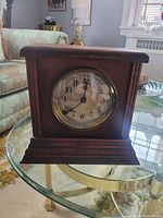 Front view of antique Sessions 8 day wooden mantel clock showing aged dial and wooden case.