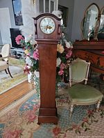 Full view of the five-foot tall antique wooden floor clock showing entire body and base.
