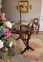 Side angle view of antique cradle showing spindle design, caster base, and carved end panels in a living room setting.