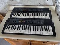 Two Casio CTK-50 keyboards stacked, showing full key range and control panels.