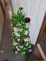 Image showing front angle of 4ft artificial Christmas tree decorated with red ornaments and white pinecones.