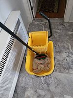 Top view of yellow mop bucket, mop head placed inside the bucket.