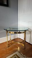 Side view of the round glass top end table with brass base showing the table height, glass thickness, and detailed legs.