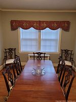 Set of two red patterned fabric cornices installed above double window, showing scalloped bottom edge and traditional pattern.
