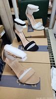 Three pairs of women's dress shoes in black, nude, and silver, each new in its box and with ankle strap and cushioned inner sole