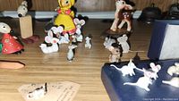 Multiple miniature ceramic mice and other animal figurines, including a small Bambi figurine, arranged on a wooden surface.