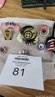 Collection of various collectible pins including patriotic U.S., Olympics, and Love Ride pins alongside a Rolling Stones metal ponytail holder.
