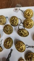Close-up photo of several gold-tone brass eagle buttons showing embossed eagle detail