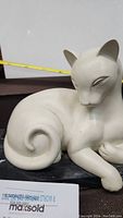 Side view of cat figurine showing curled tail and smooth finish on marble base