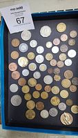 Collection of approximately 50 mixed coins from various countries showing diversity in size, color and material.