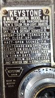 Close-up photo of the exposure guide plate on Keystone 8mm Camera Model K-8 showing aperture and exposure instructions for various lighting and scene conditions including brilliant sunlight, bright open scenes, hazy open scenes, light shade and open scenes on dull days, scenes in heavy shade, and guidance for color film and winter use.