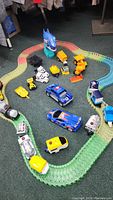 Full loop of multi-colored flexible track with multiple toy cars and construction vehicles placed inside.