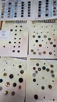 Multiple sample cards each displaying a collection of fashion buttons, plus loose buttons scattered on the surface